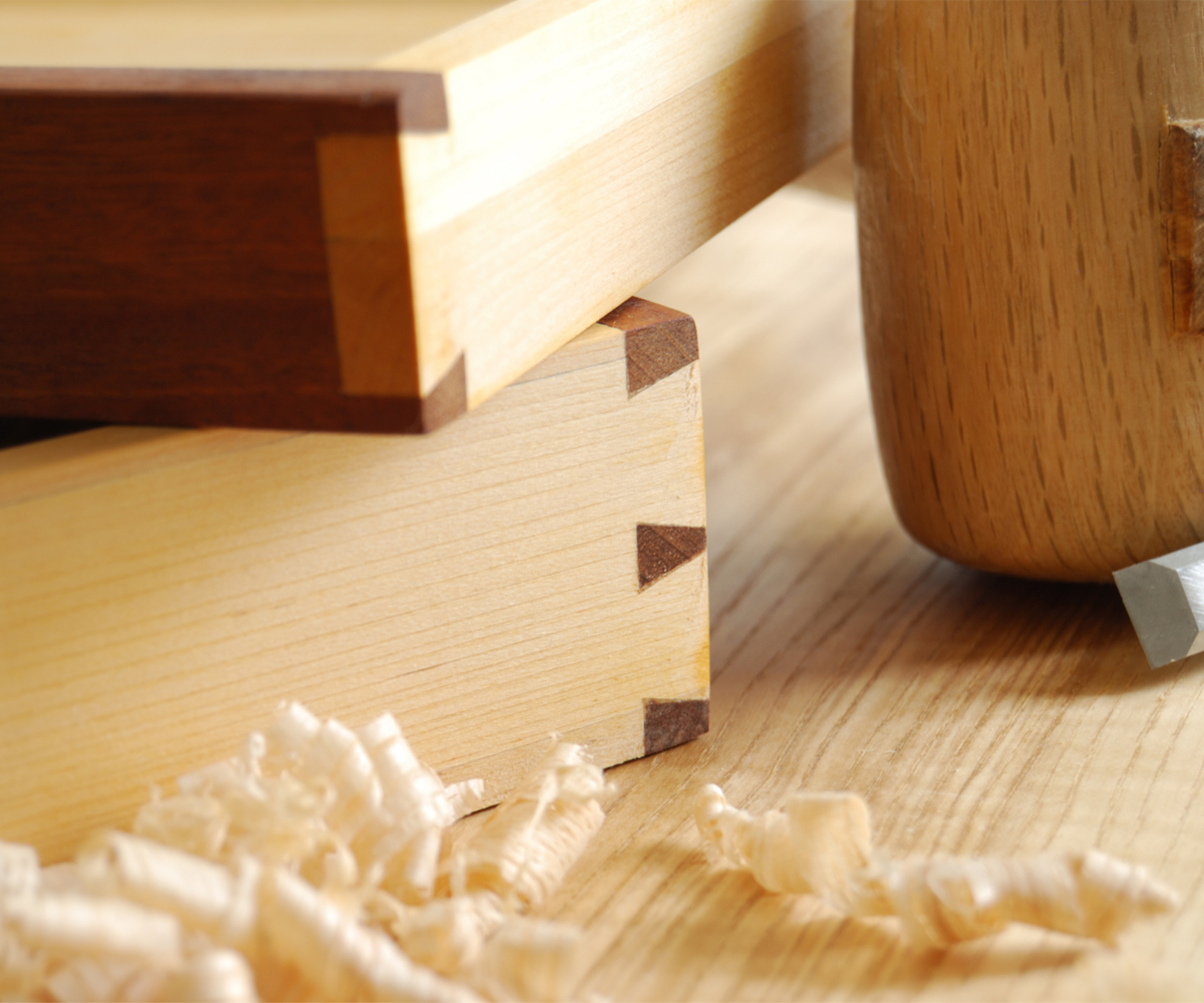 Close-up of dovetail drawer joints with wood shavings, showing Amish-style solid wood joinery.