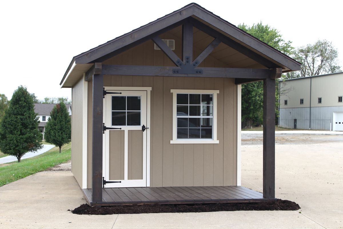 Porch-style Amish shed kit with timber gable, windowed door, and primed siding on concrete.